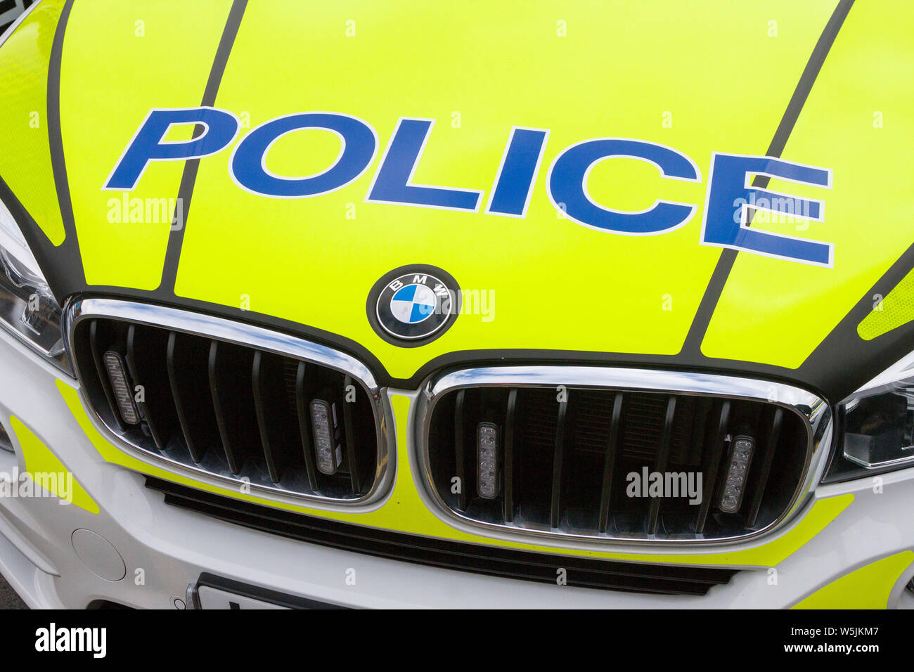 Police logo on the bright yellow fluorescent bonnet of a BMW police patrol car Stock Photo