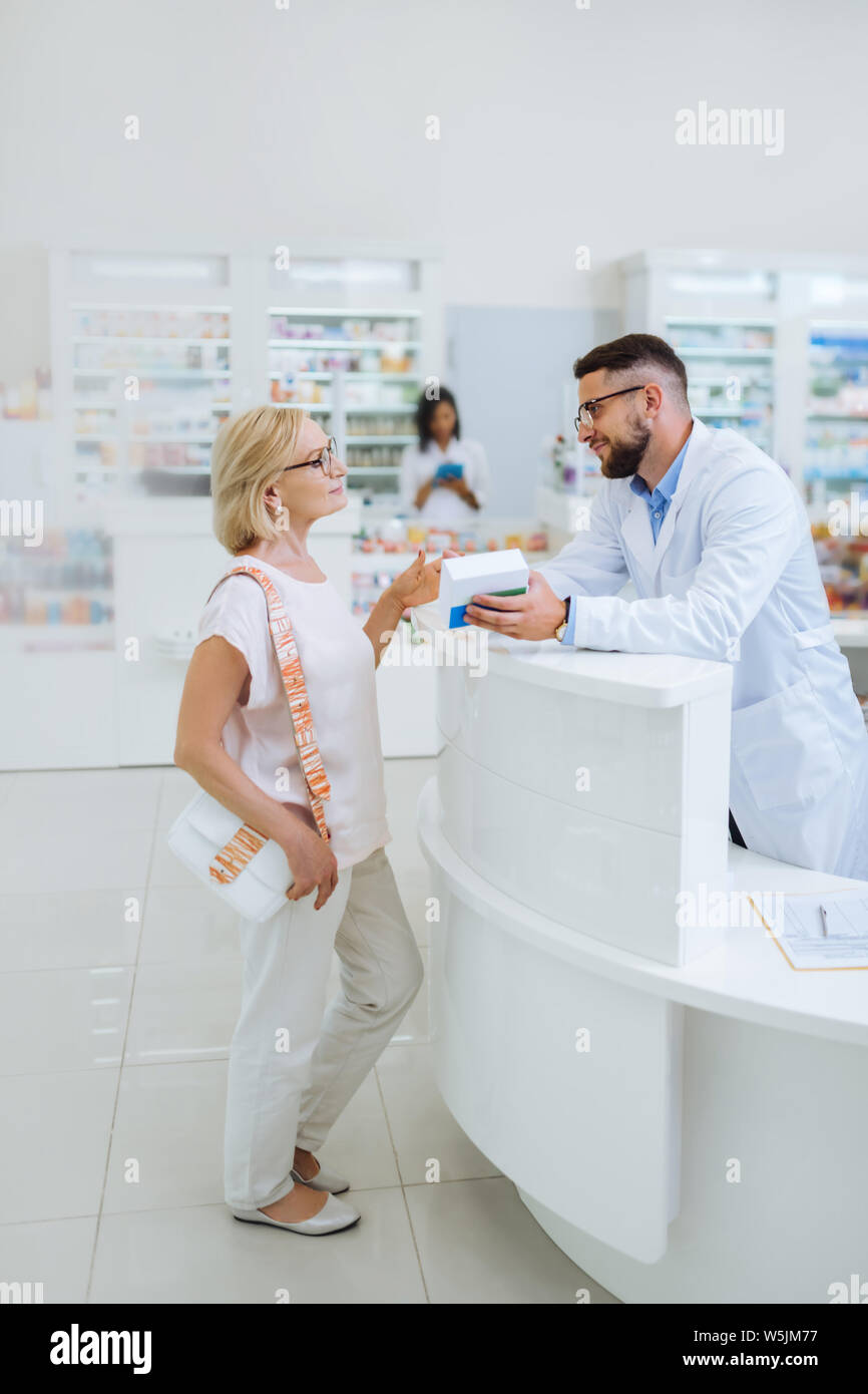 Pretty blonde female person talking to pharmacist Stock Photo