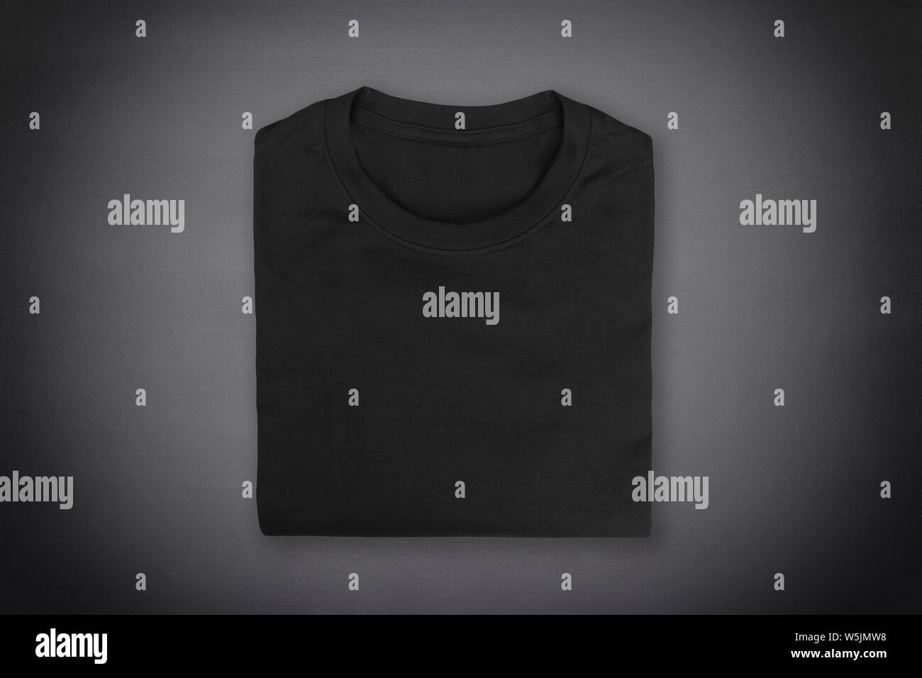 Black folded t-shirt on black chalkboard background with vignette Stock Photo