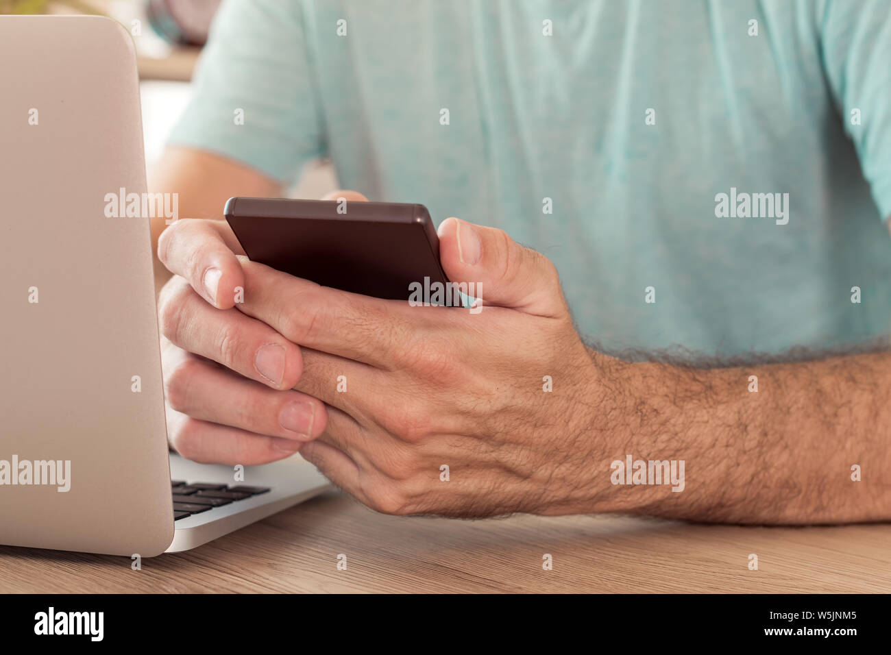 Freelancer using smart phone in home office, close up of hands, selective focus Stock Photo