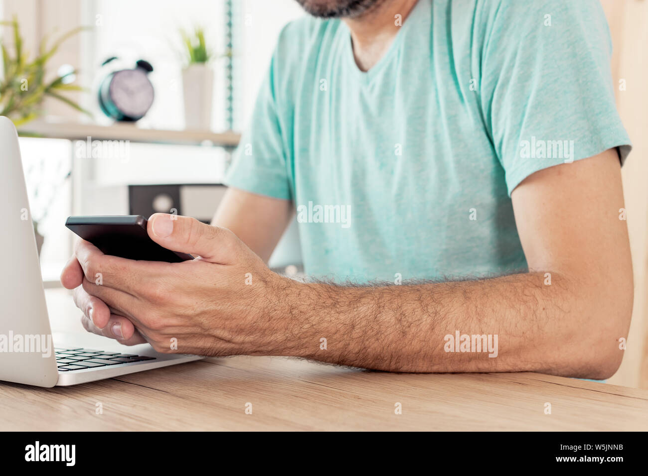 Freelancer using smart phone in home office, close up of hands, selective focus Stock Photo
