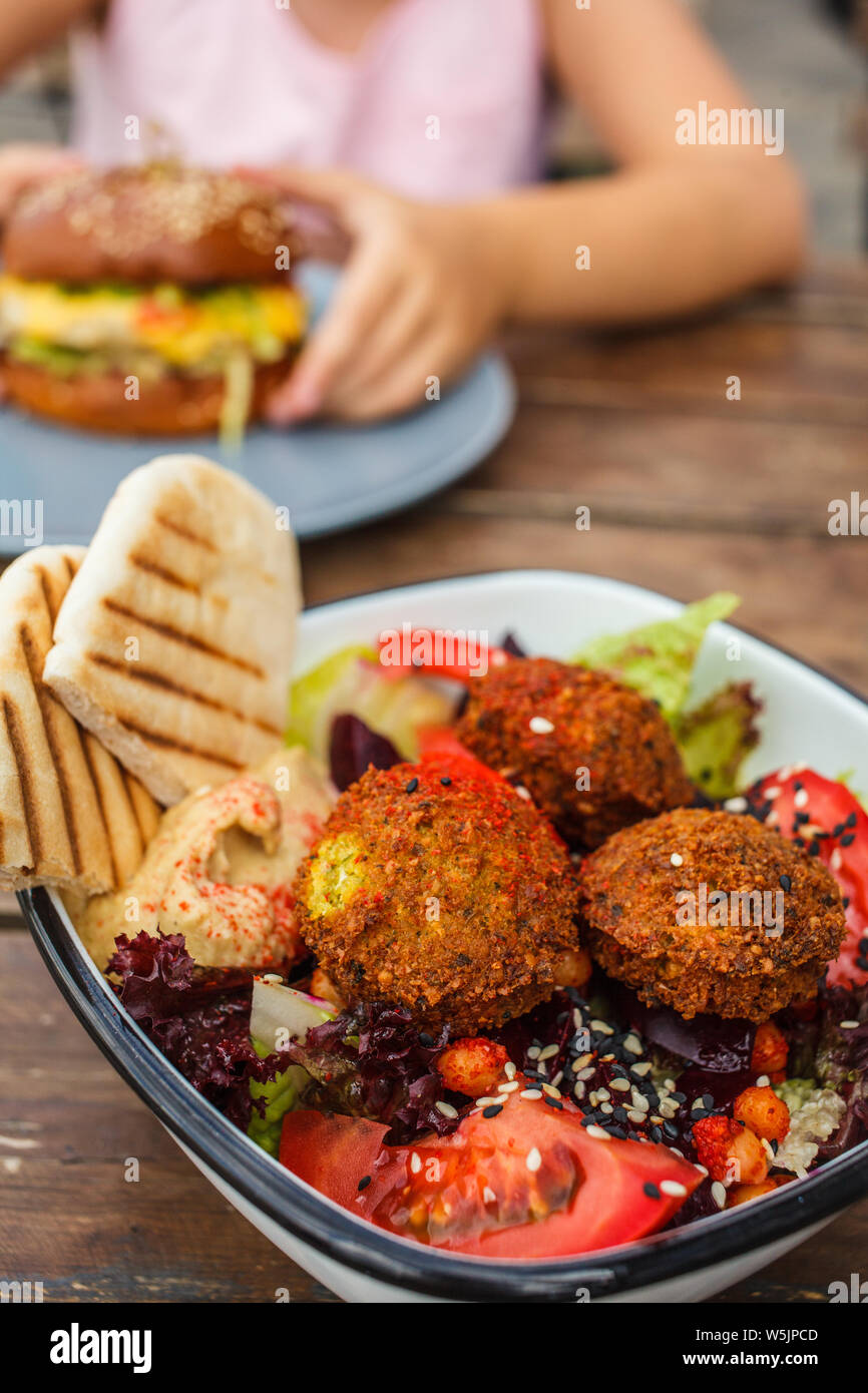 Israeli street food. Falafel salad with hummus, beetroot and vegetables in a bowl in a restaurant. Stock Photo
