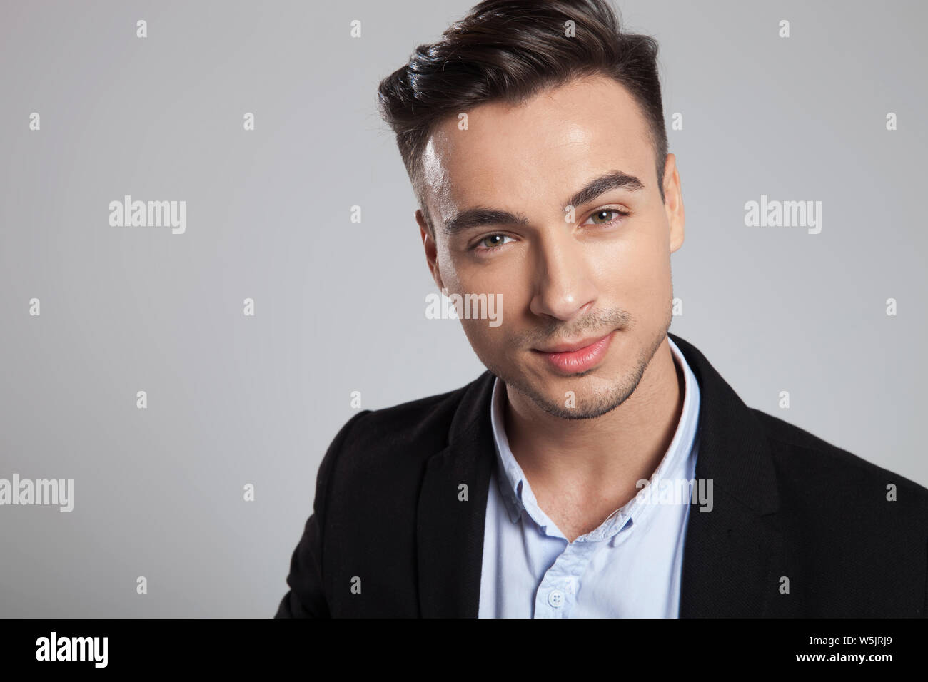 portrait of attractive young businessman wearing black suit smiling ...
