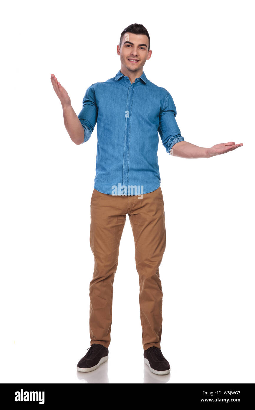 handsome man in blue shirt makes a gesture while standing on