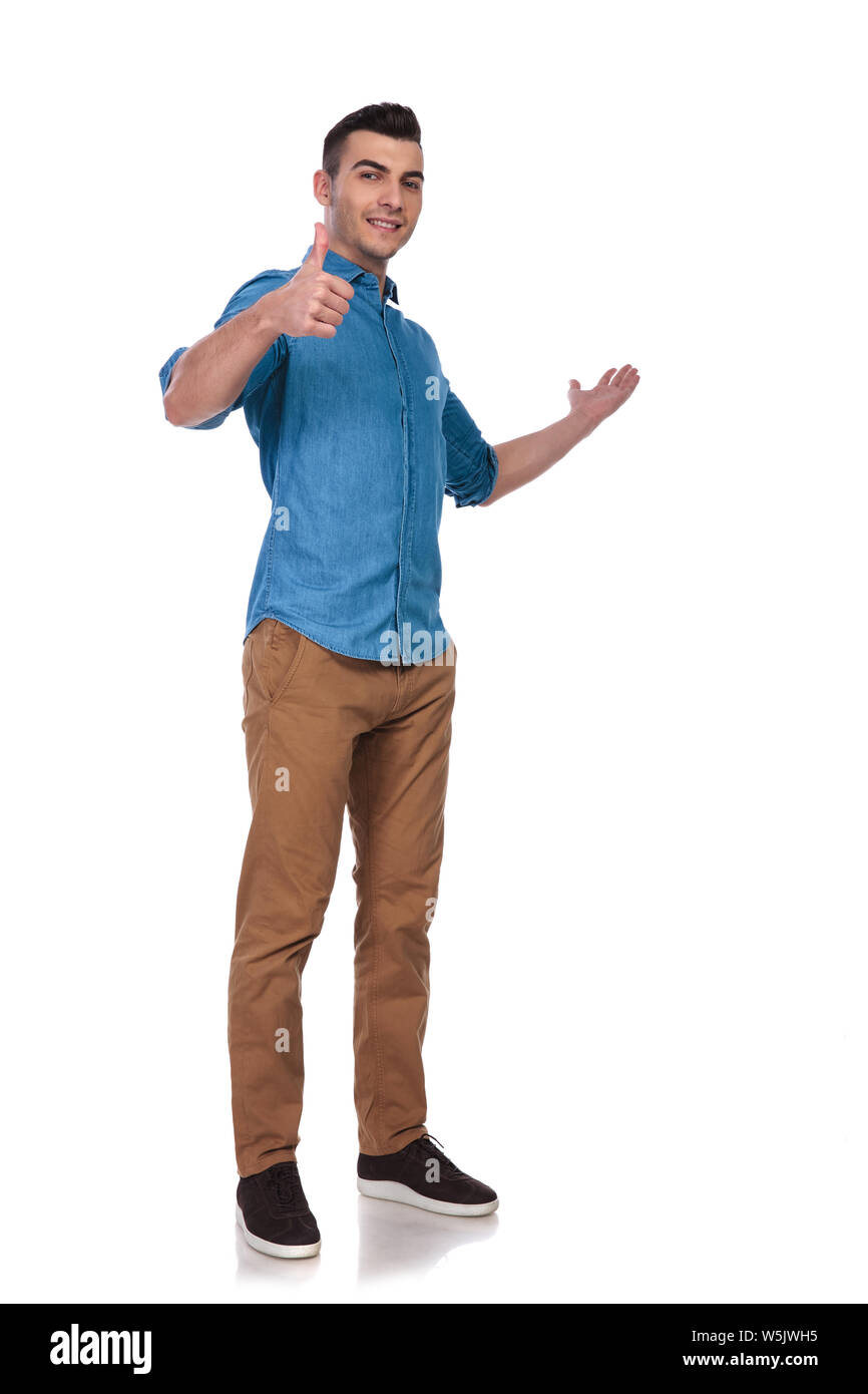 young casual man presents to side and makes ok sign while standing on ...