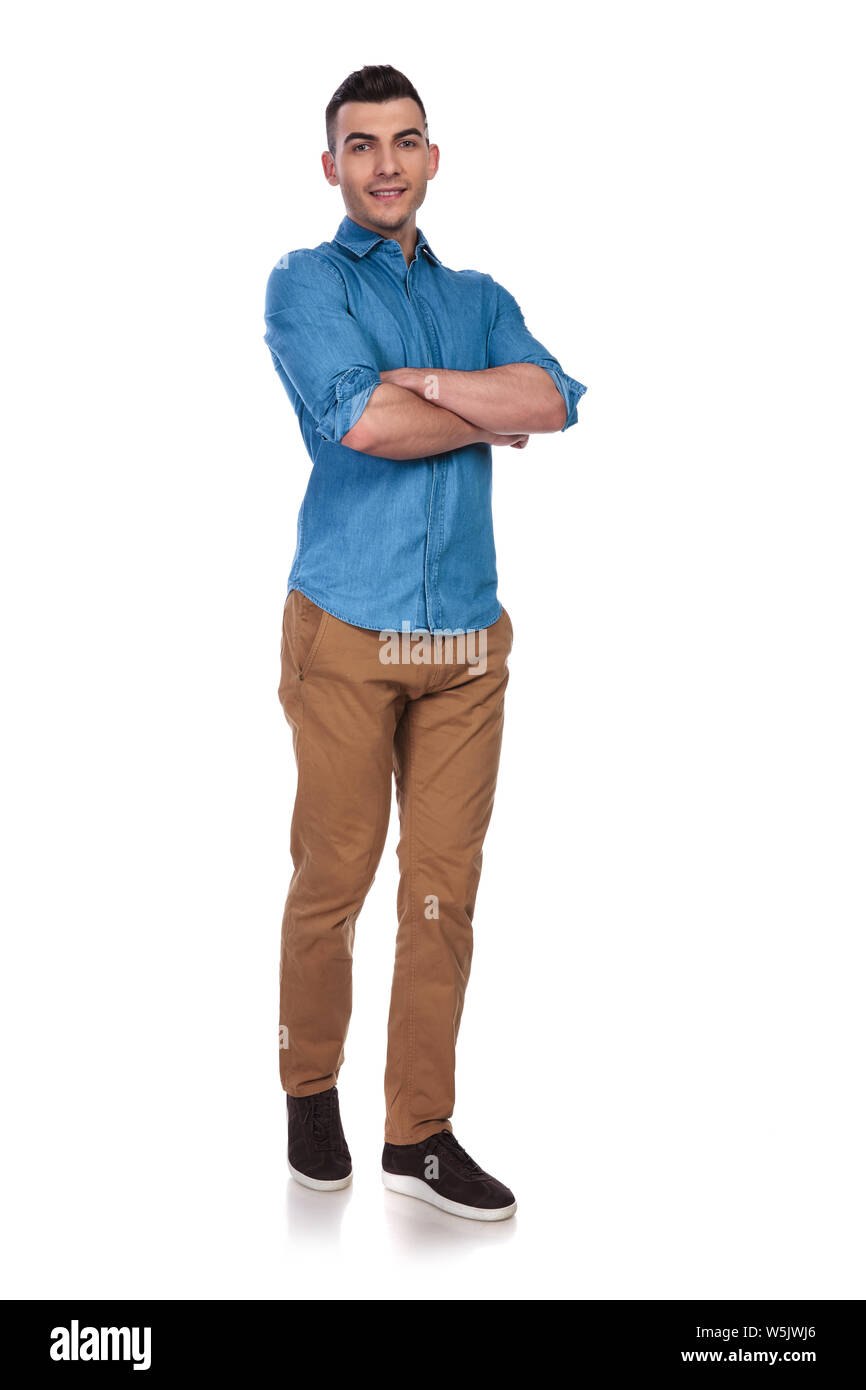 young casual man standing with folded hands on white background and stepping forward Stock Photo