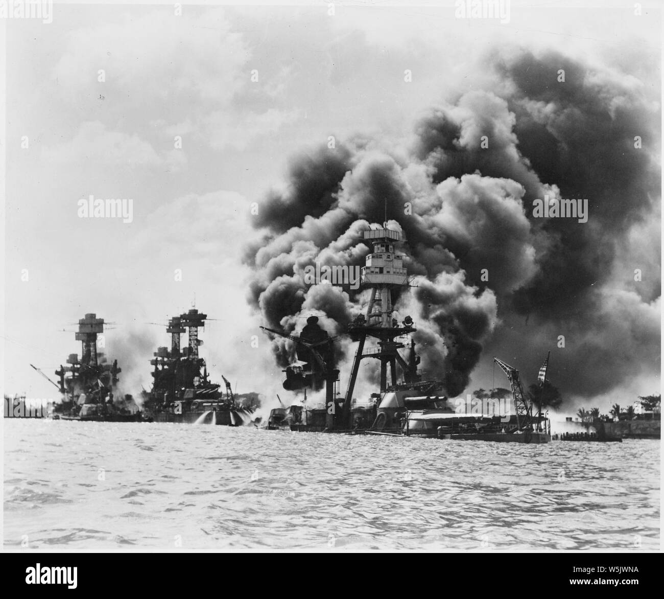 Aftermath of a Japanese sneak attack on these three stricken U.S. battleships; from left to right: USS West Virginia (severely damaged), USS Tennessee (damaged), and the USS Arizona (sunk) Stock Photo
