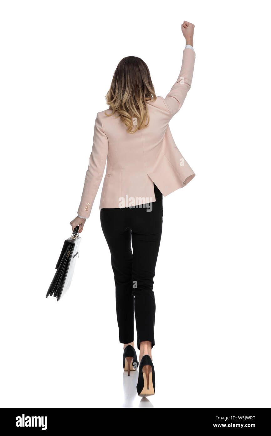 rear view of businesswoman celebrating while walking to work on white background, full body picture Stock Photo