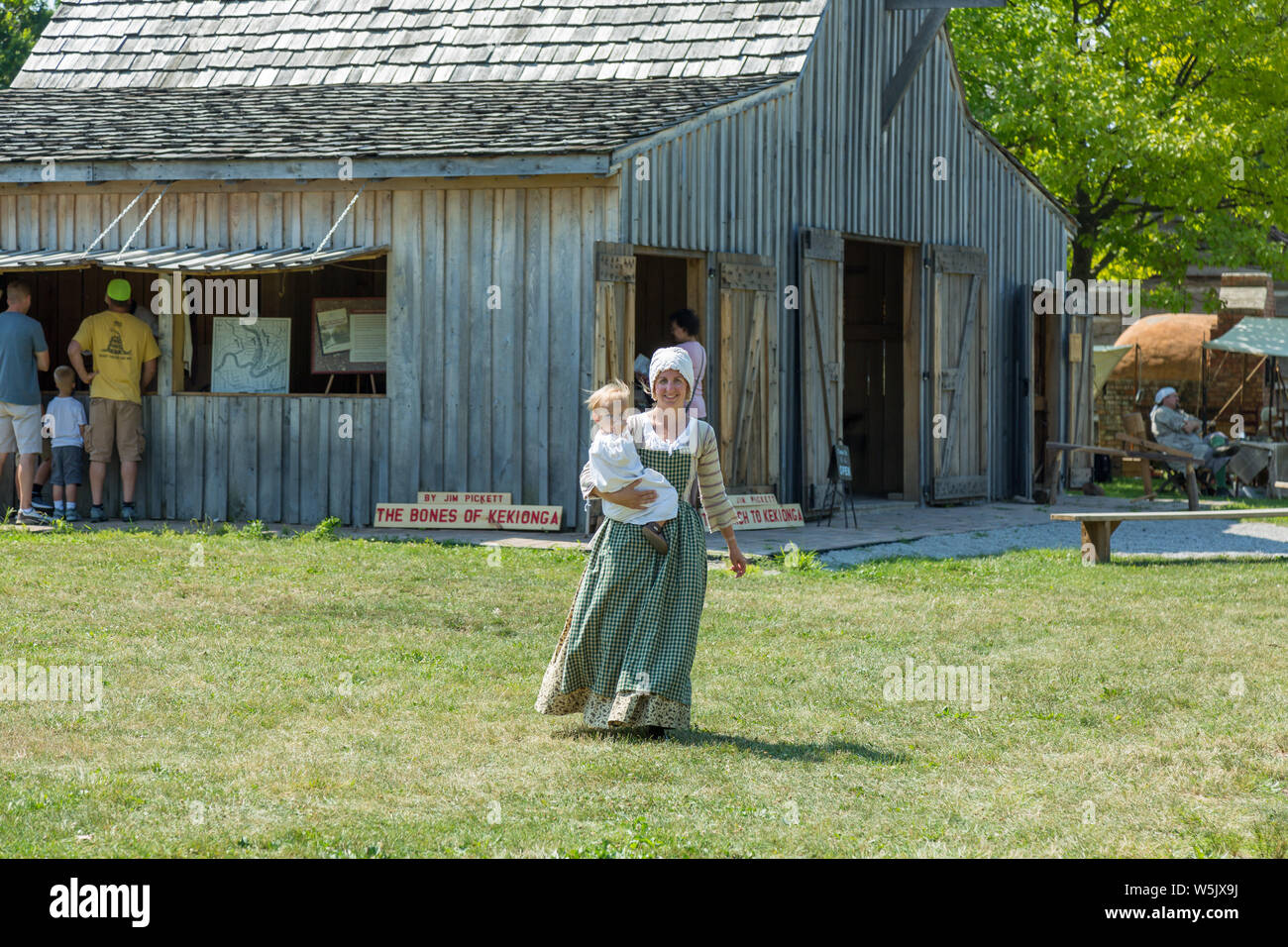 A reenactress carries her child during a reenactment at Historic Old Fort Wayne in Fort Wayne, Indiana, USA. Stock Photo