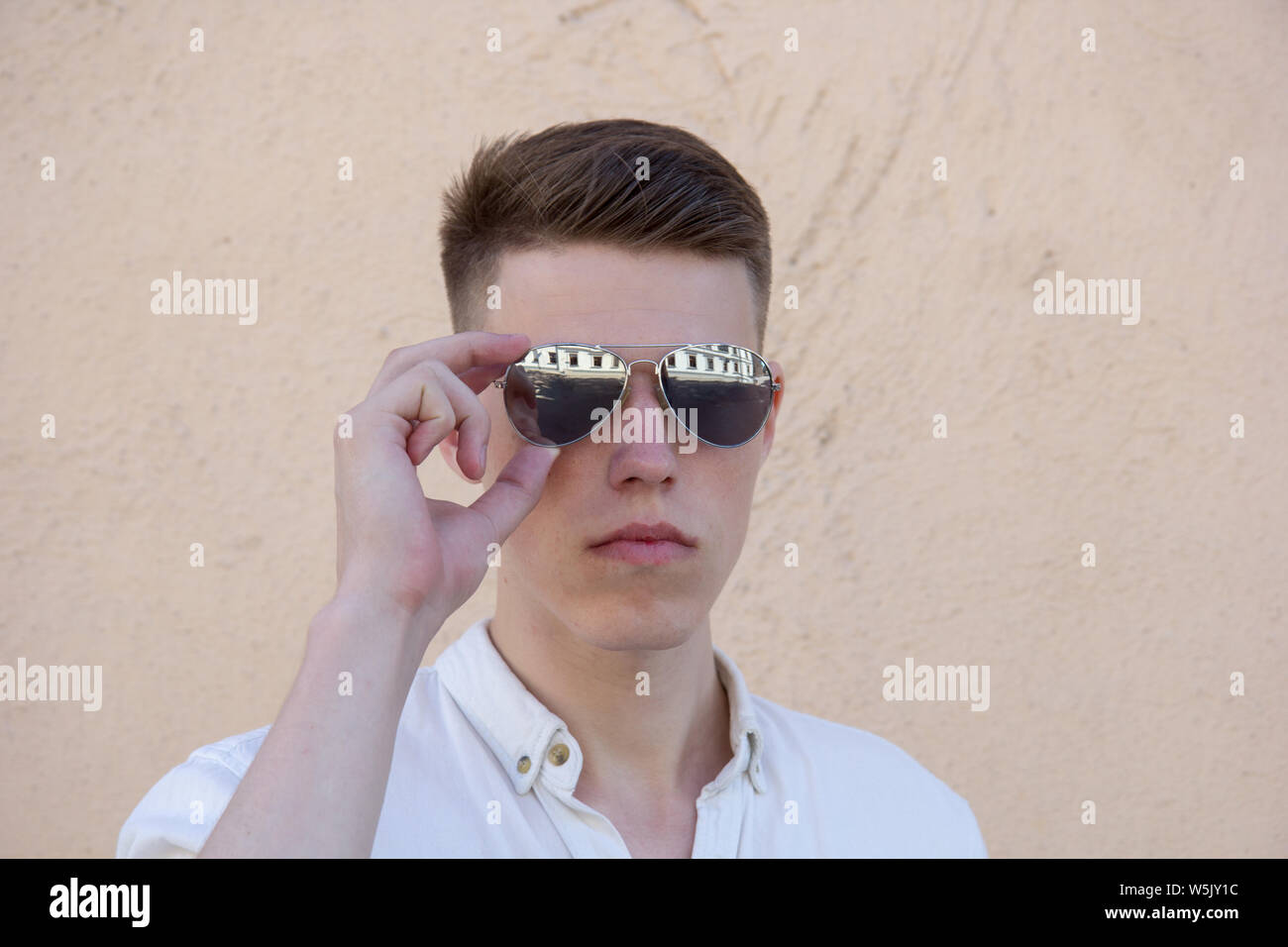 portrait of a handsome man dressed in white shirt against yellow wall ...