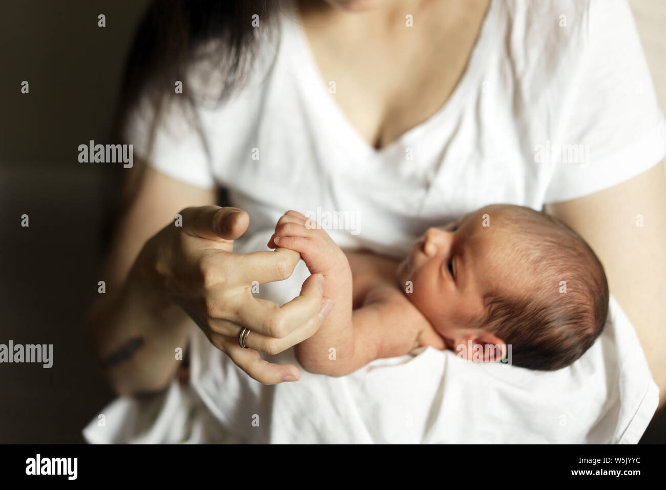 Little hand of a newborn in a large hand of mother. Stock Photo