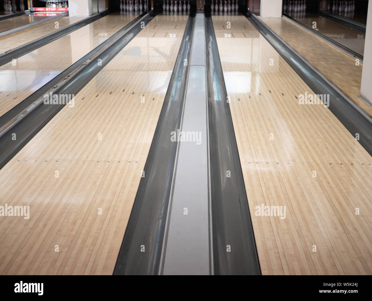 two lanes tracks at bowling club with bunch of bowls pins at far