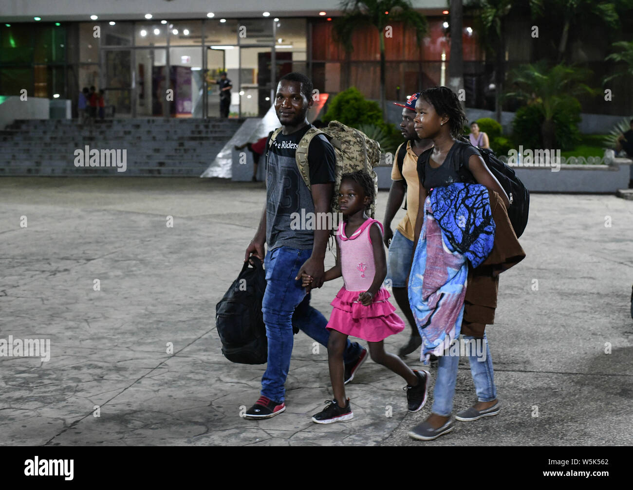 July 26, 2019, Tapachula, Chiapas, Mexico: The new global melting pot: a family from Cameroon walks accross main plaza, founding father Miguel Hidalgo in downtown Tapachula, as two Bangladeshi migrants. Mexico has witnessed an increase of migrants crossing the country to reach the US, and now hundreds wander the streets of this southern Mexican city, which is becoming one more new global melting pot. Credit: Miguel Juarez Lugo/ZUMA Wire/Alamy Live News Stock Photo