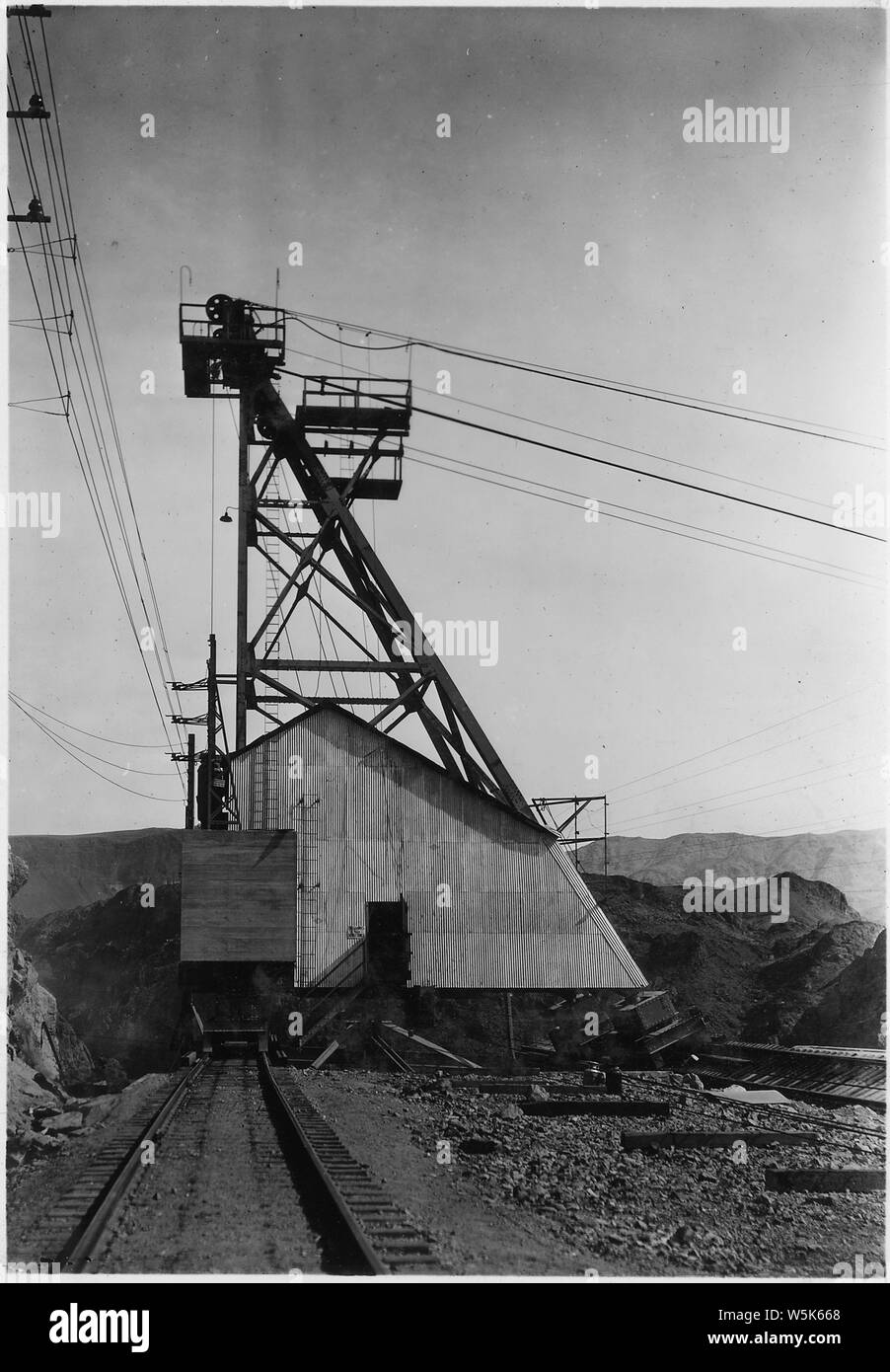 Boulder Canyon movable cableway tower operating over Hoover damsite. This photograph shows a typical installation. Note thrust rail and cable arrangement to provide lateral movement. Concrete counter weight seen at left.; Scope and content:  Photograph from Volume Two of a series of photo albums documenting the construction of Hoover Dam, Boulder City, Nevada. Stock Photo