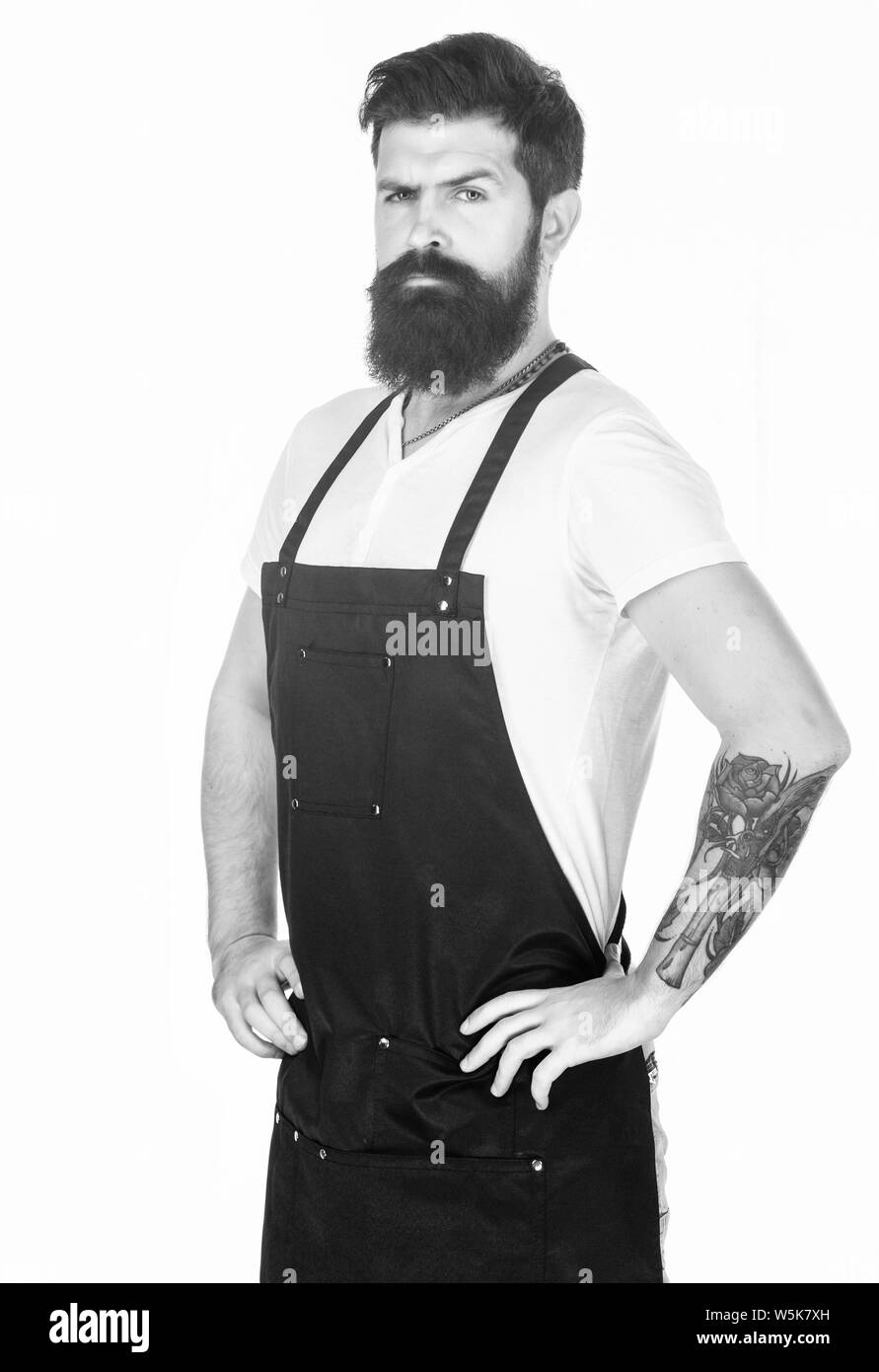 Theres no doubting he looks good. Bearded man wearing barber or cooking apron. Long bearded man keeping arms crossed. Hipster with bearded face. Bearded barber or cook. Stock Photo