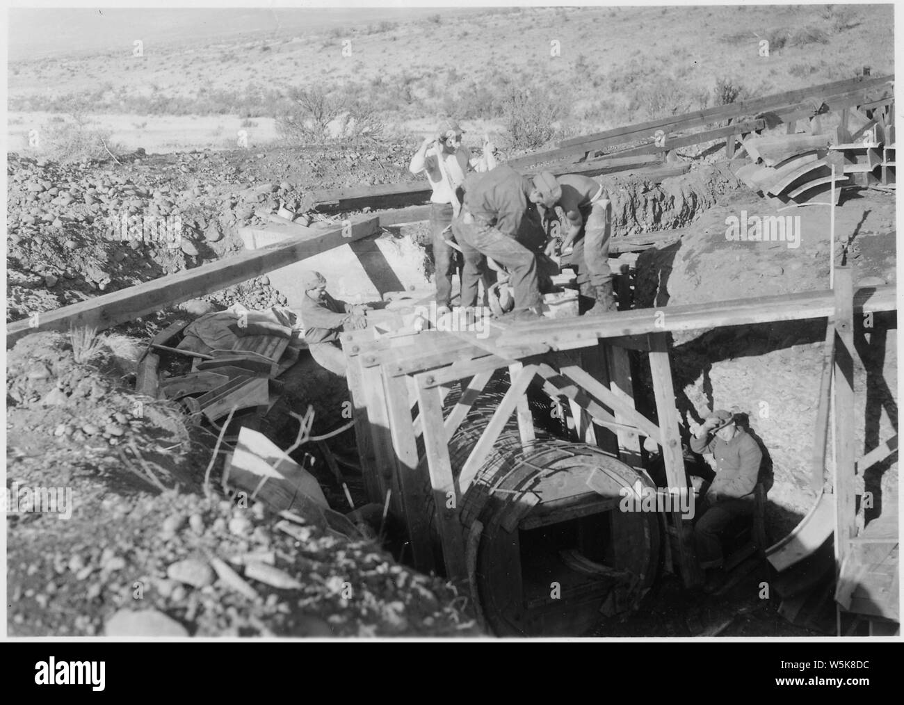 CCC Camp BR-66 Yakima-Tieton Project: Photo of construction of 54 inch monolithic reinforced concrete siphon. Enrollees are placing forms and steel for curved portion of barrel at outlet end. J. S. Moore photographer. Stock Photo