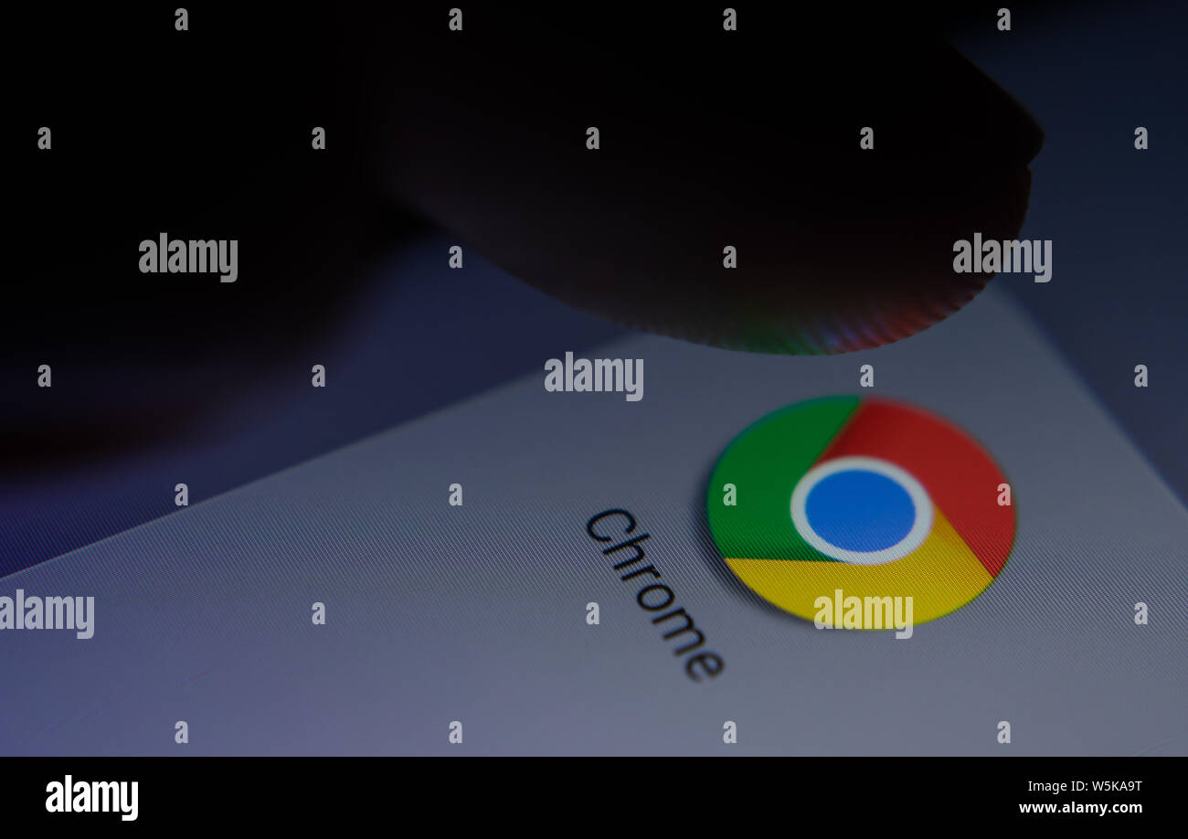 Chrome app icon on the smartphone screen with visible pixels and the finger about to launch it. Stock Photo