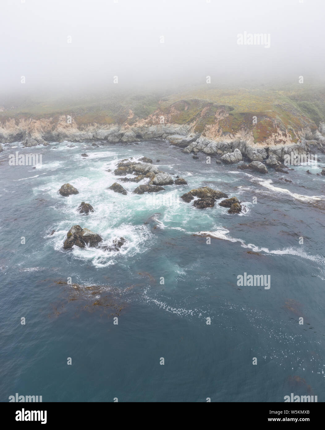 Seen from a bird's eye view, the cold waters of the Pacific Ocean wash against the rocky yet beautiful coast south of Monterey in Northern California. Stock Photo