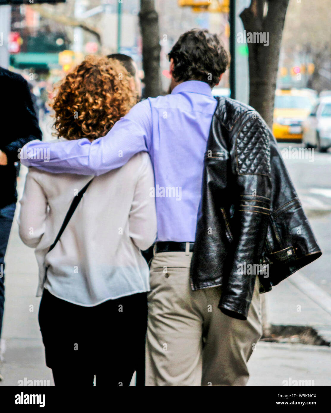 A man walking with his arm around his girlfriend shoulders and his cout