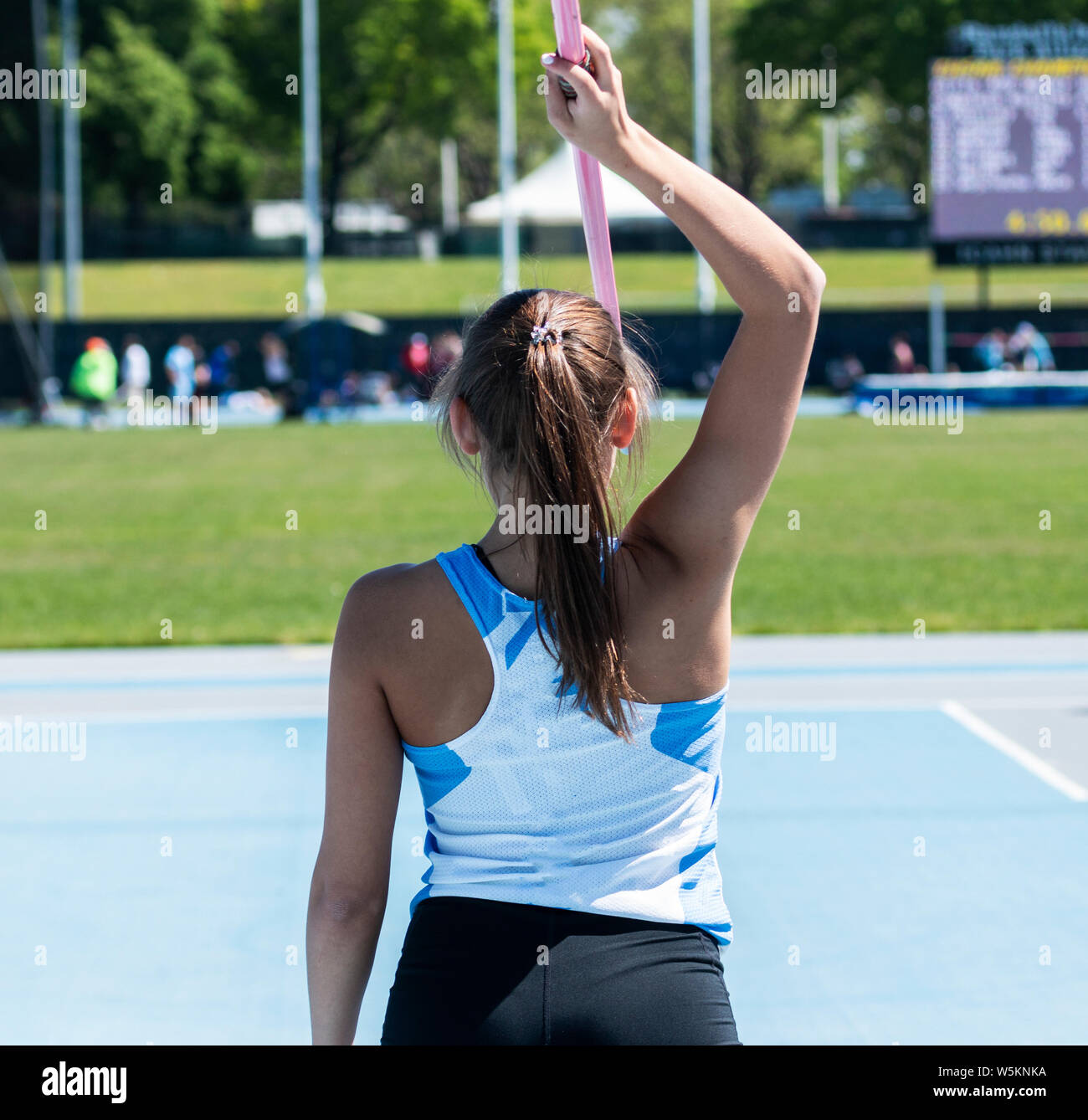 A high school girl holding a javelin overhead as she gets ready to compete in a track and field event. Stock Photo