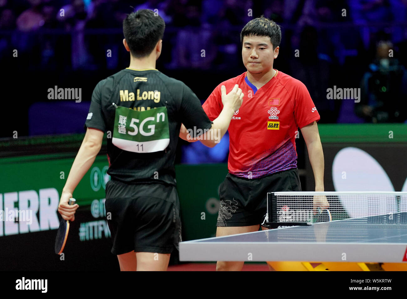 Ma Long of China shakes hands with Liang Jingkun of China after their semifinal match of Men's Singles during the Liebherr 2019 ITTF World Table Tenni Stock Photo