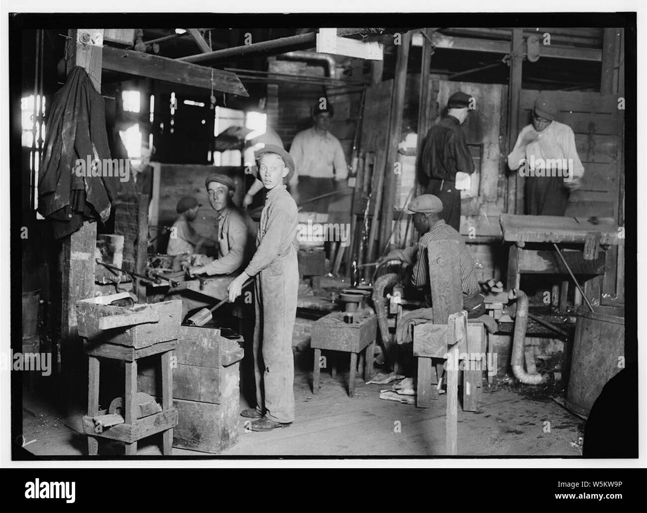 Cumberland Glass Works, Bridgeton, N.J. A young 'holding-mold boy' is seen, dimly, in middle distance to left of centre. Negroes, Greeks and Italians are being employed in many glass houses. Stock Photo