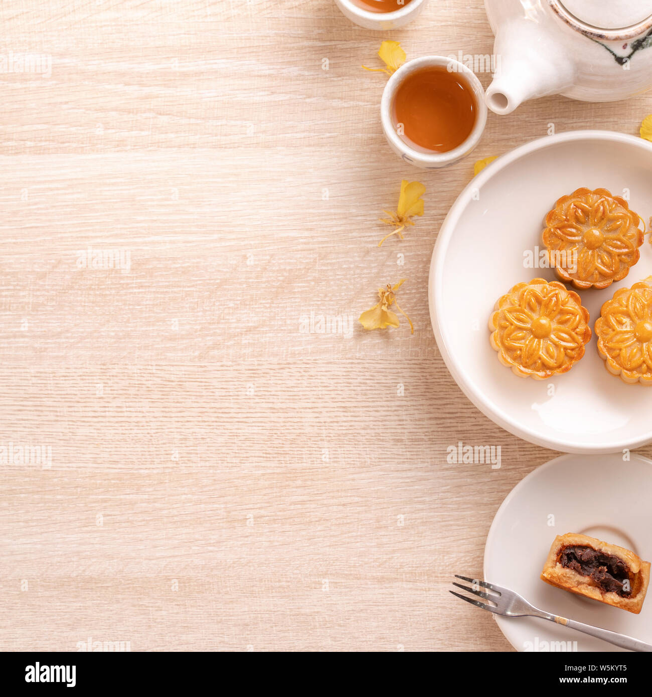 Delicious moon cake for Mid-Autumn festival with beautiful pattern, decorated with yellow flowers and tea. Concept of festive afternoon pastry design Stock Photo