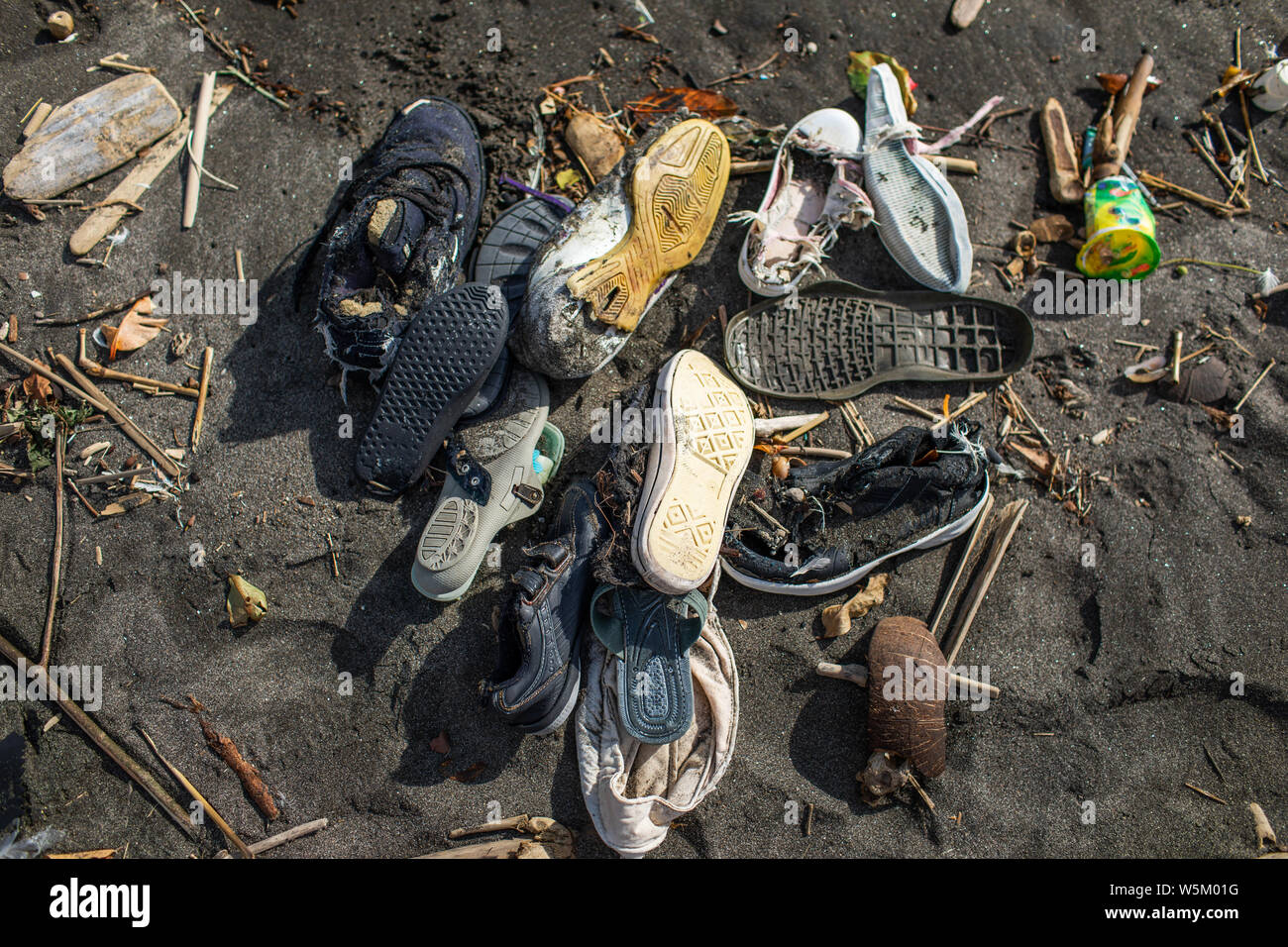 Environmental pollution. Heap of used rubber shoes on the beach in Bali