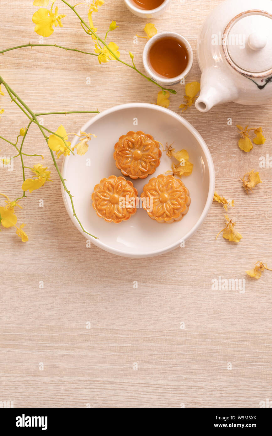 Delicious moon cake for Mid-Autumn festival with beautiful pattern, decorated with yellow flowers and tea. Concept of festive afternoon pastry design Stock Photo