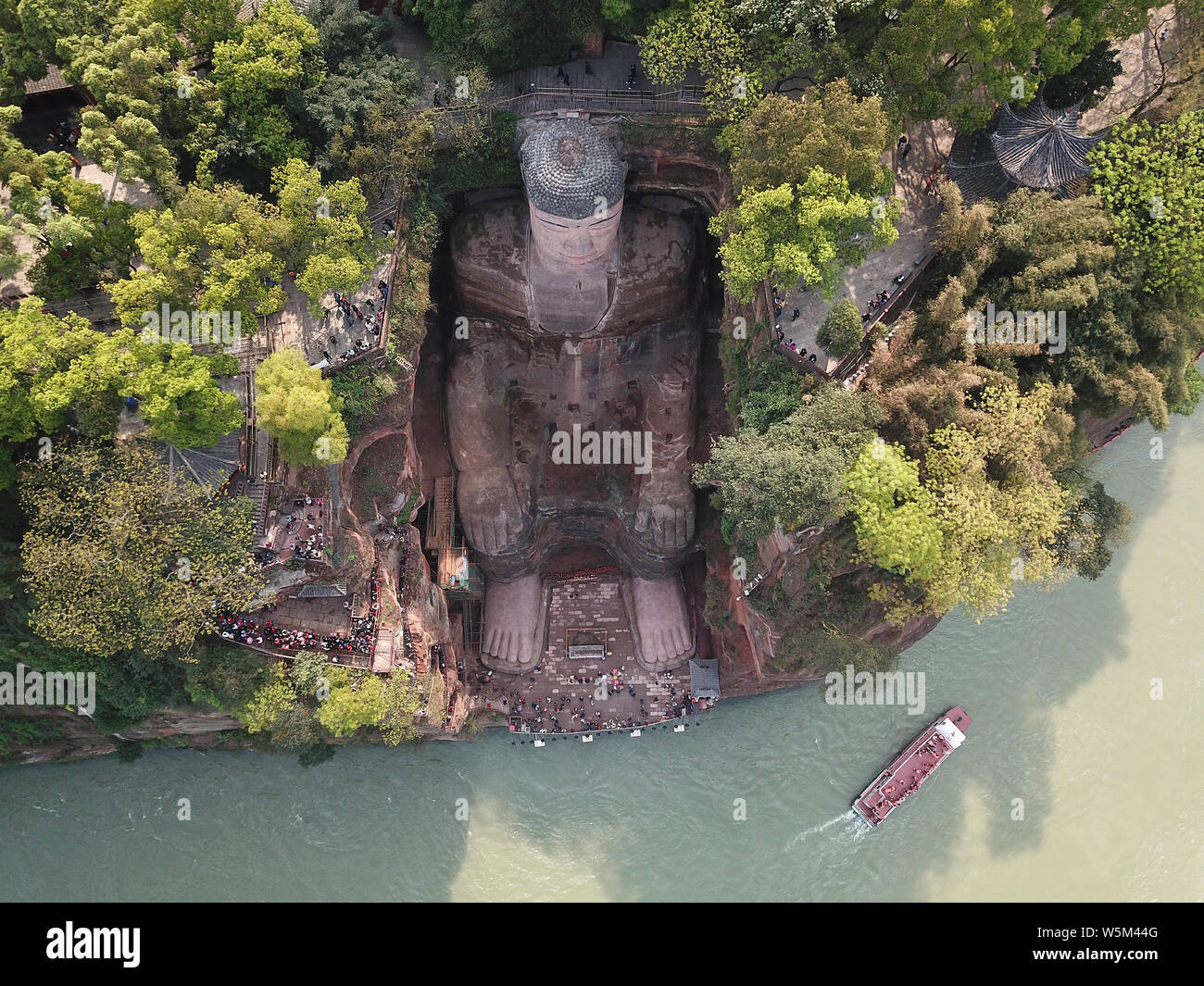 Tourists view the Leshan Giant Buddha after renovating its damaged chest and abdomen and remove algae on its face in Leshan city, southwest China's Si Stock Photo