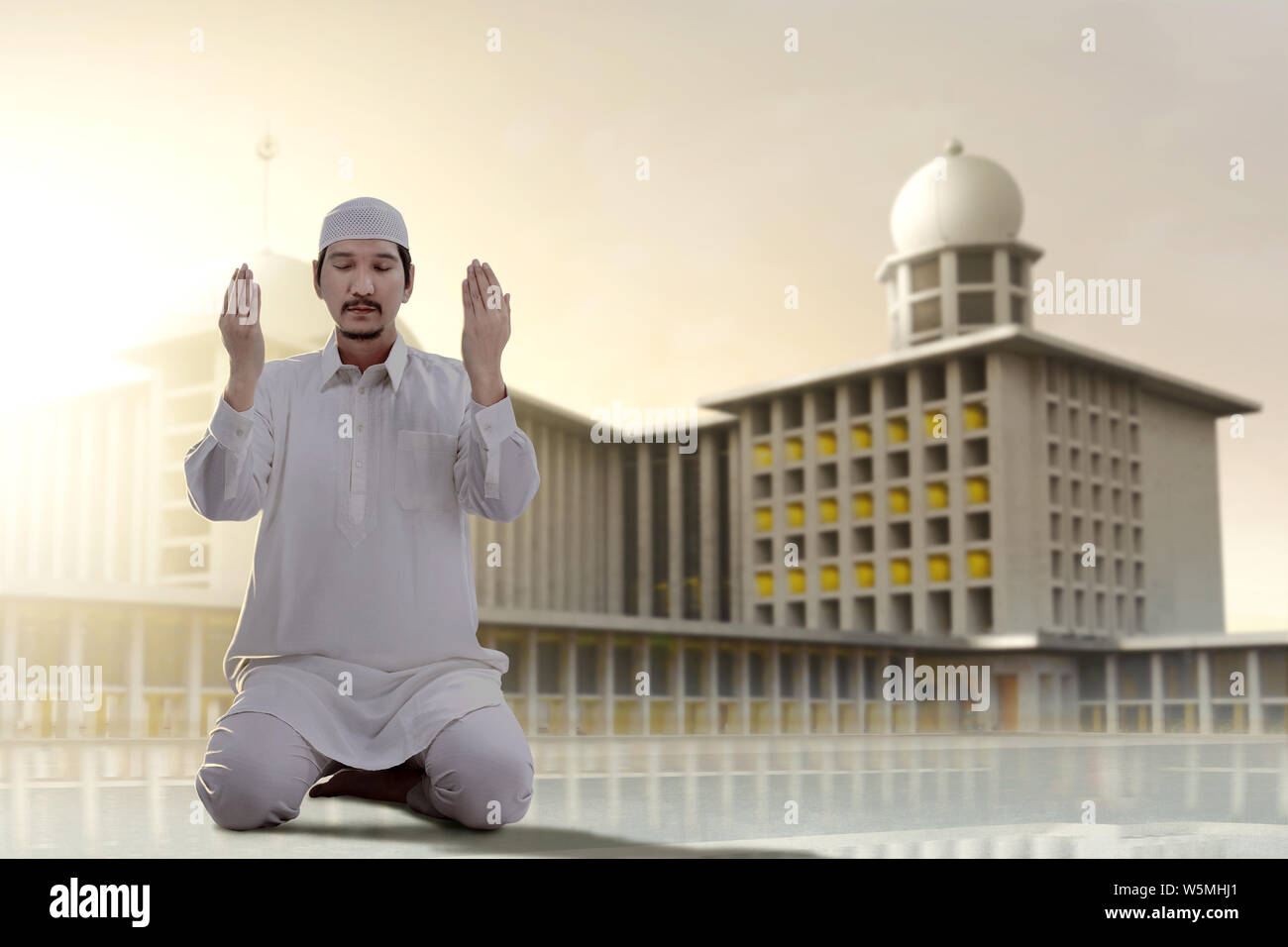 Asian Muslim man sitting in pray position while raised hands and