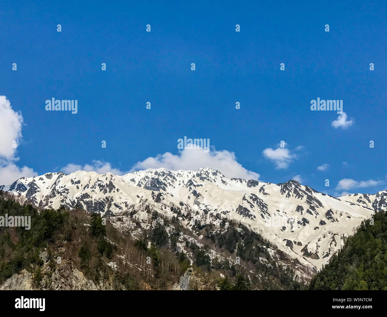 Beautiful snow mountain view with blue sky and cloud on Tateyama Kurobe alpine route, Japanese alps in Japan. Stock Photo