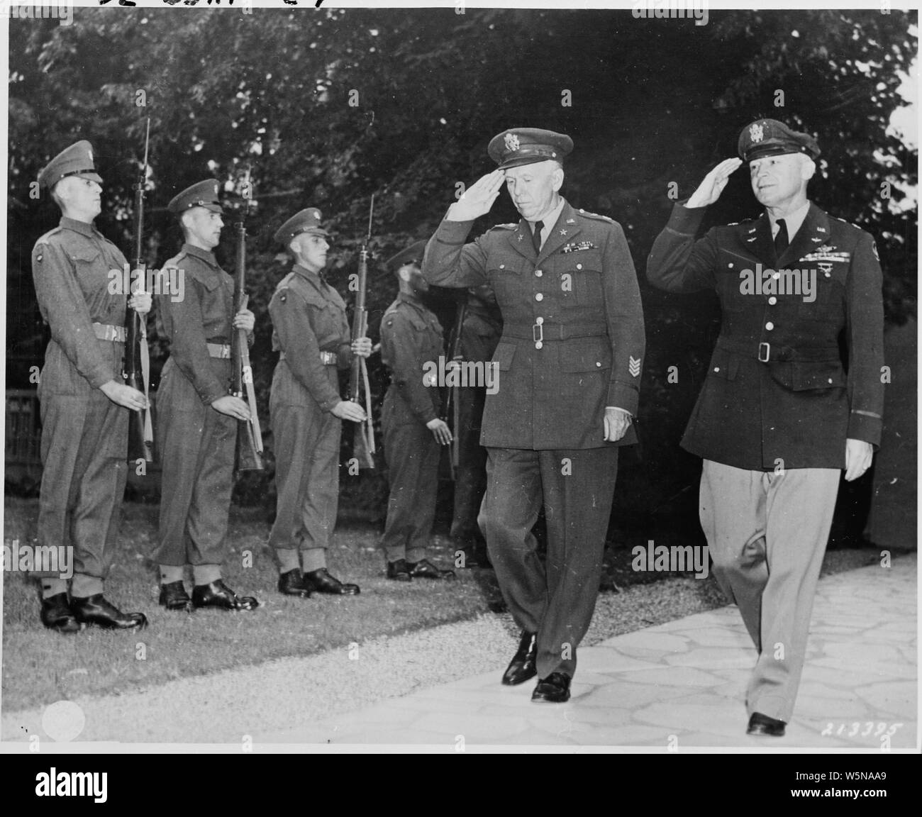 Gen. George C. Marshall, U. S. Army Chief of Staff, and Gen. Henry Hap Arnold, Commanding General, U. S. Army Air Forces, arrive at the residence of Prime Minister Winston Churchill for a dinner given by the British Prime Minister for President Truman and Soviet leader Josef Stalin during the Potsdam Conference. The two generals return the salute of the Guard of Honor formed by a detachment of Scots Guards of the British Brigade of Foot Guards Stock Photo