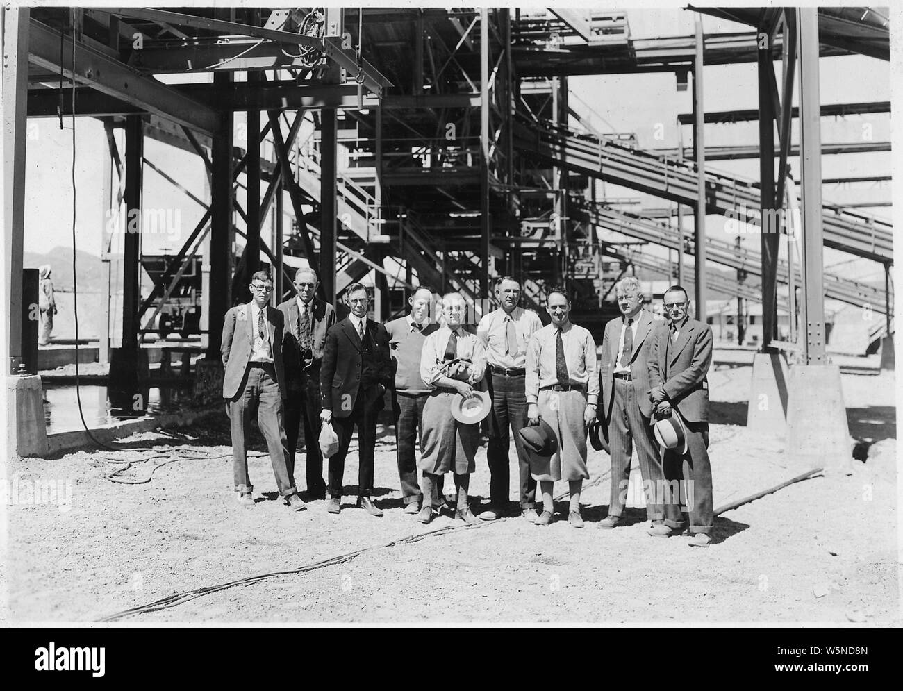Group including members of the Concrete Consulting Board at the Six Companies' screening and washing plant. From left to right they are: Irving Furlong, Bureau of Standards, San Francisco; B.W. Steele, Designing Engr., Bureau of Reclamation; Arthur Ruettgers, Concrete Technician; T.M. Price, Six Co's. Supt. of railroad and screening plant; P.H. Bates, Bureau of Standards, Washington, D.C.; Ralph Lowry, Field Engineer, Bureau of Reclamation; Prof. R.E. Davis, Univ. of Calif; F.R. McMillan, Portland Cement Assn., Chicago; Walker R. Young, Construction Engineer, Bureau of Reclamation.; Scope and Stock Photo