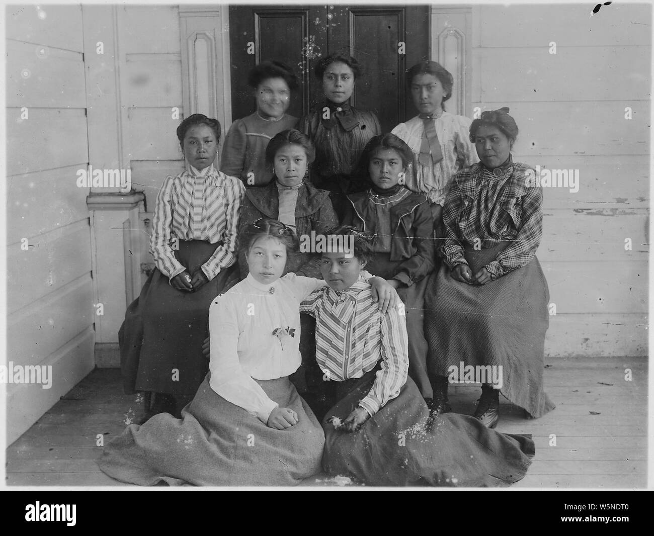 Group of young Indian women (9).; Scope and content:  Back row, center: Mrs. George Williams, sister of Alex Guthrie and niece of Josiah Guthrie. Front row, left: Ed. Benson's daughter, Alice--married Henry Rudland. Front row, right: Mrs. Frank Hamilton, adopted daughter of Ernest Milton. Center row, right: Mrs. Moses Hewson, Niece Annie Guthrie. Others Unidentified. Stock Photo