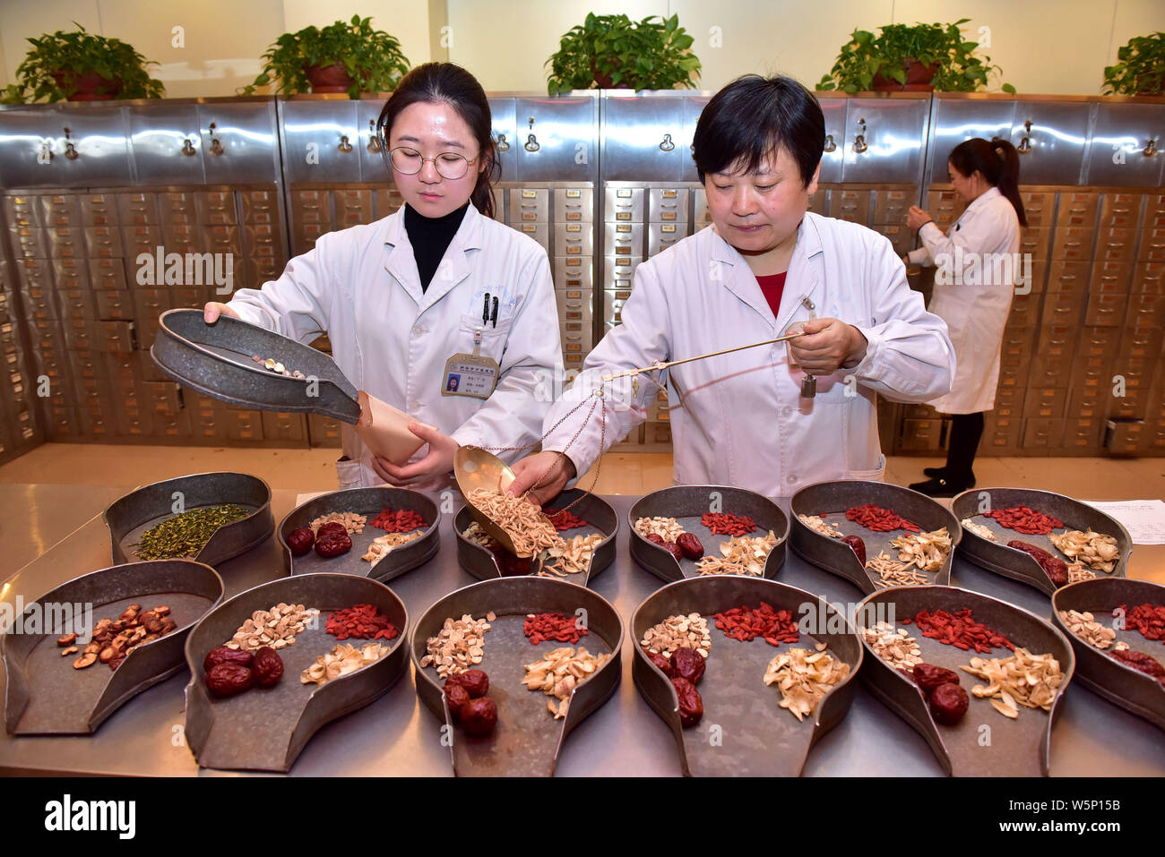 --FILE--Chinese pharmaceutists dispense traditional Chinese medicine at a TCM pharmacy in Shijiazhuang city, east China's Hebei province, 21 December Stock Photo
