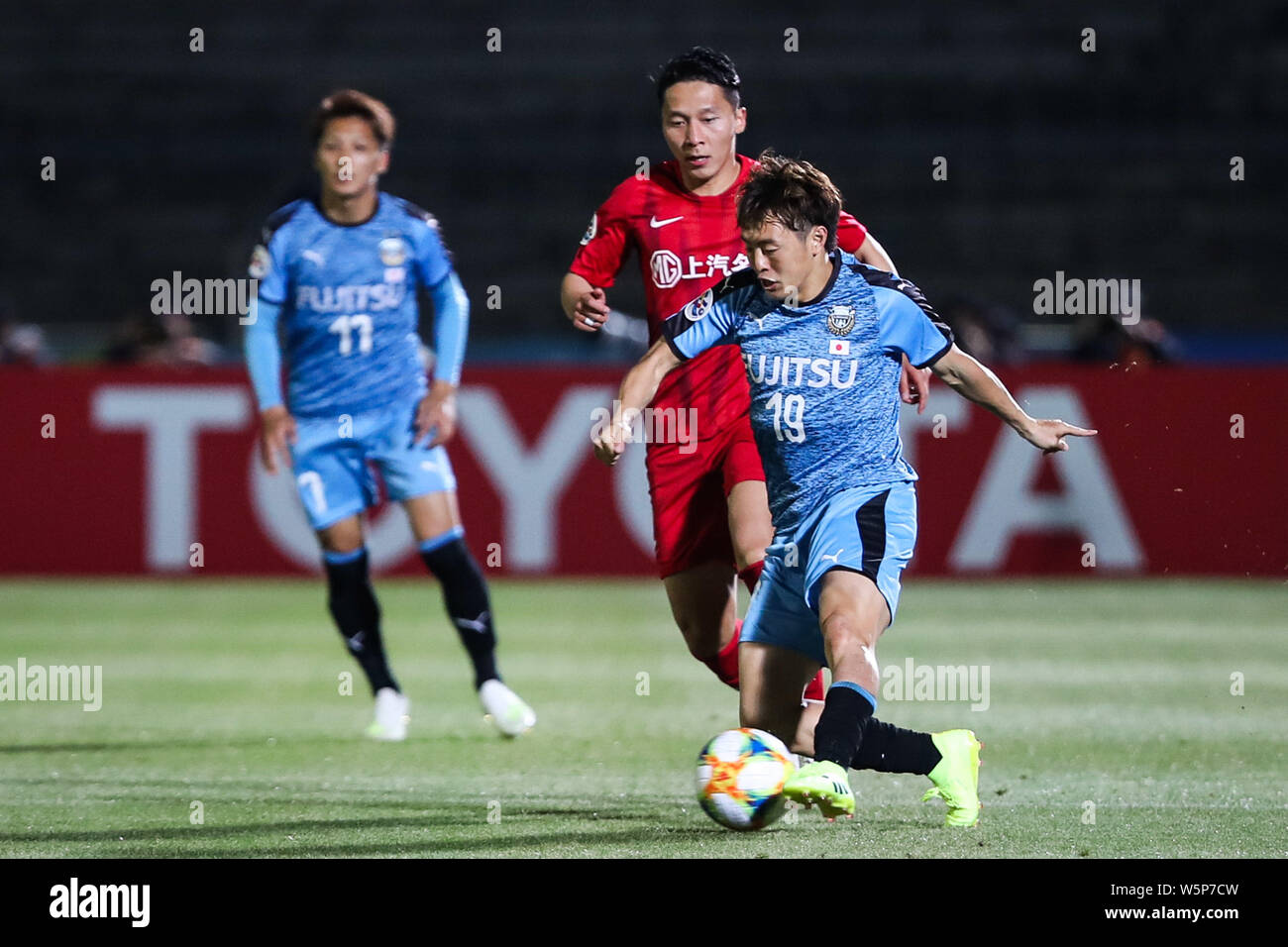 Manabu Saito, left, of Japan's Kawasaki Frontale F.C. passes the ball against a player of China's Shanghai SIPG in the 5th round of group H match duri Stock Photo