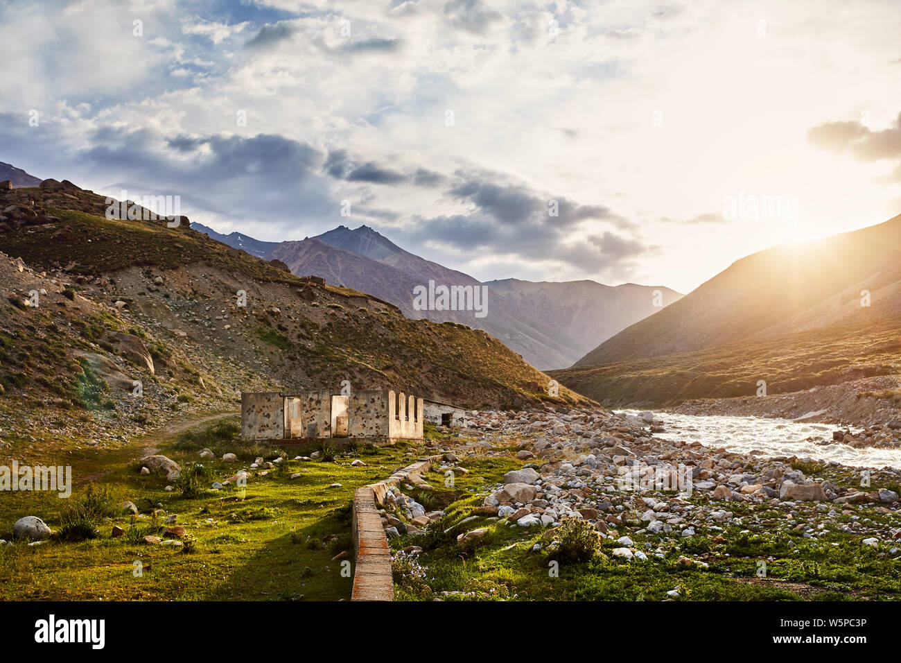 Ruined house near the river in mountain valley at sunrise in Kyrgyzstan Stock Photo