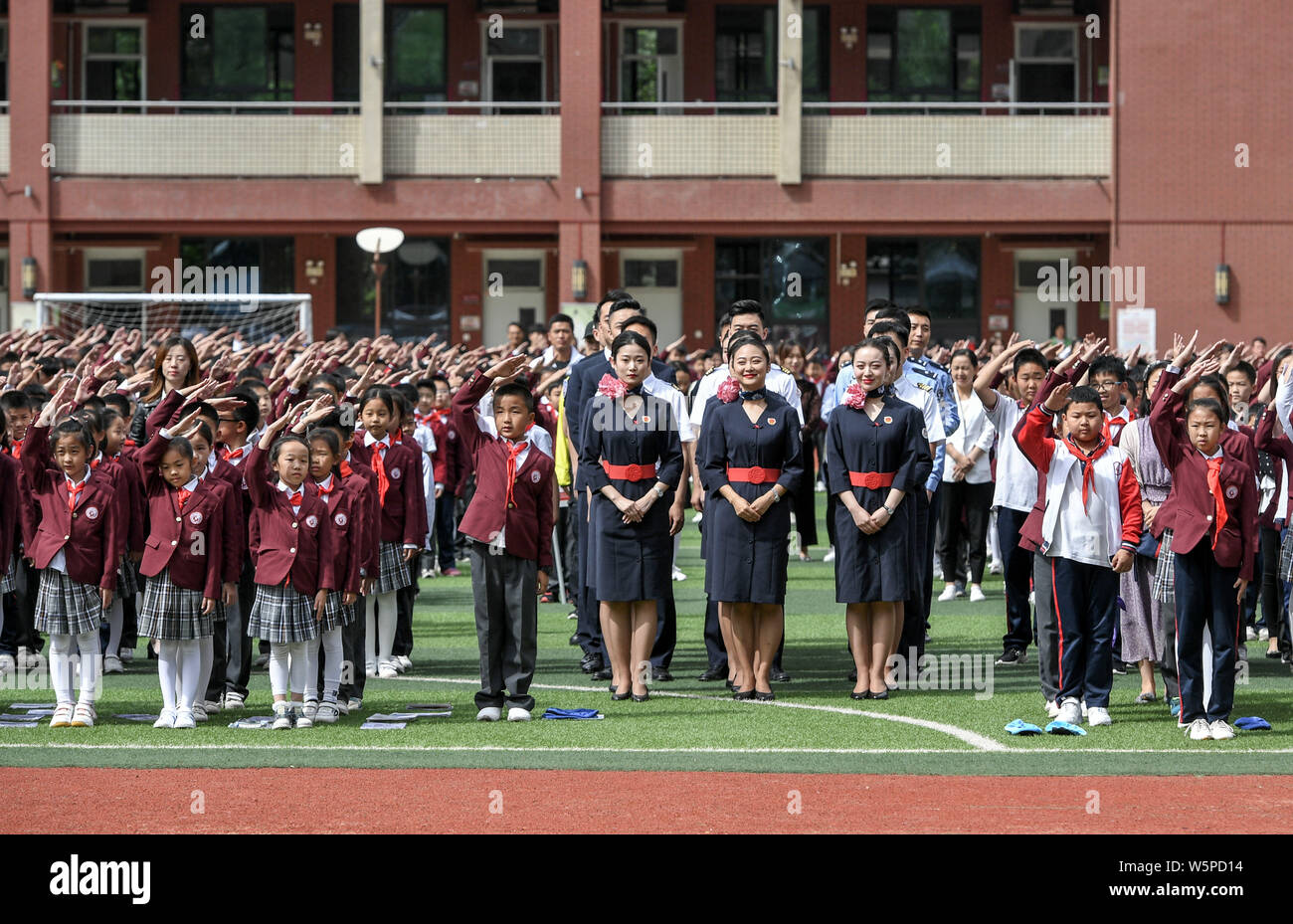Primary school students, flight attendants and pilots from China Eastern Airlines gather to encircle a national flag on the Chinese Valentine's Day in Stock Photo