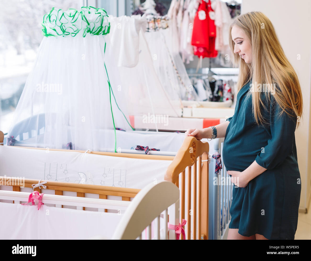 Pregnant girl chooses a baby cot in the store Stock Photo Alamy