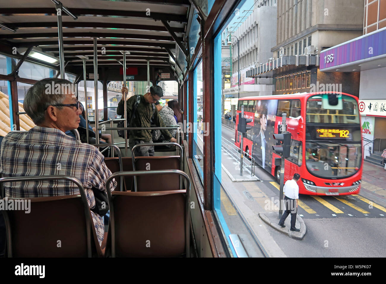 --FILE--Passengers sit in a double-decker tram travelling on the road in Hong Kong, China, 3 December 2017. Stock Photo