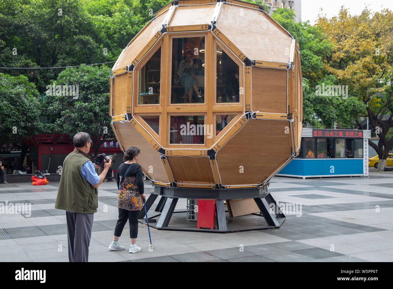 Pedestrians look at a bookstore featuring the shape of space capsule on a shopping street in Chongqing, China, 5 May 2019. Stock Photo
