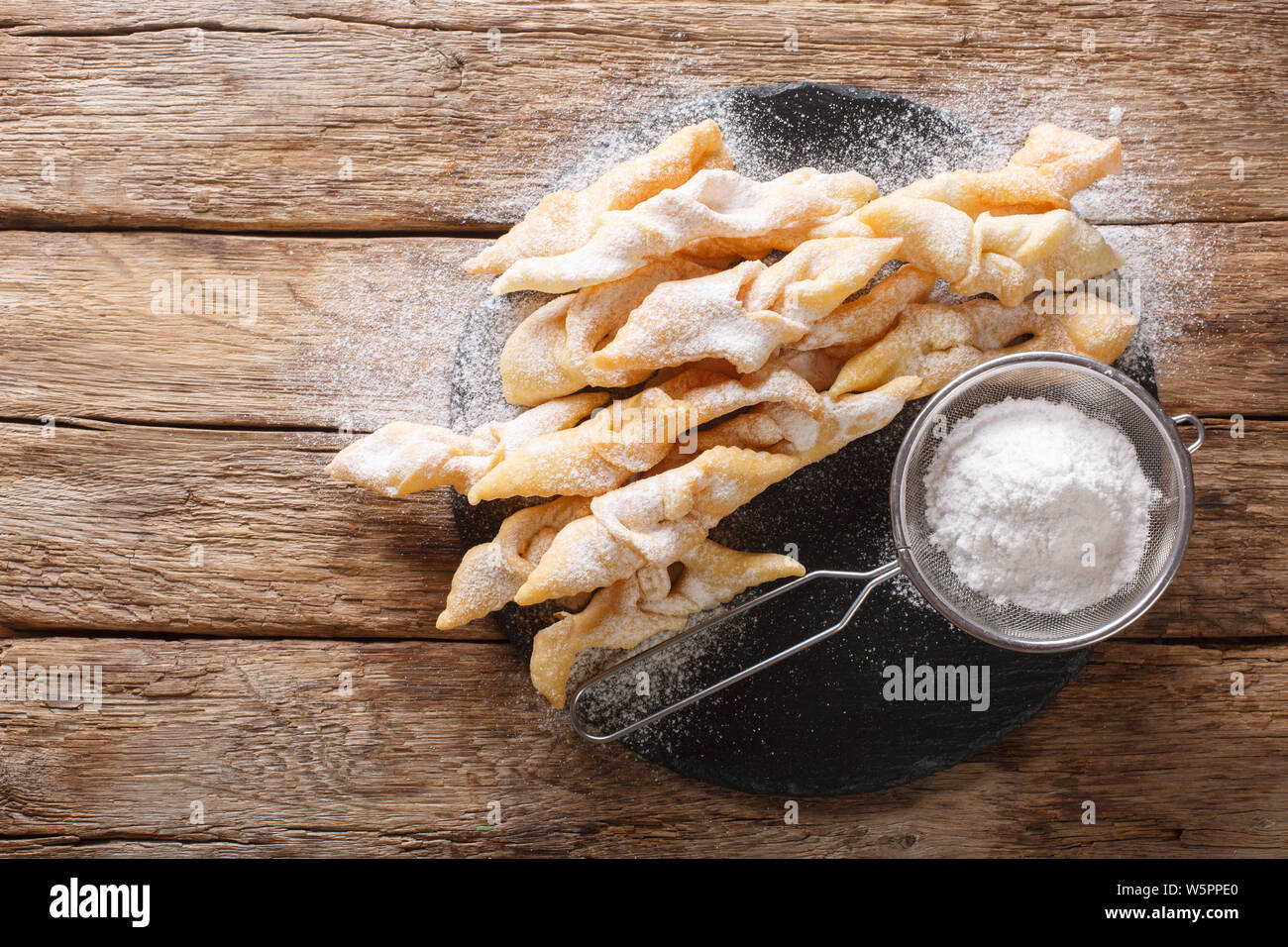 Traditional dessert Angel Wings Dusted with powdered sugar close-up on the table. horizontal top view from above Stock Photo