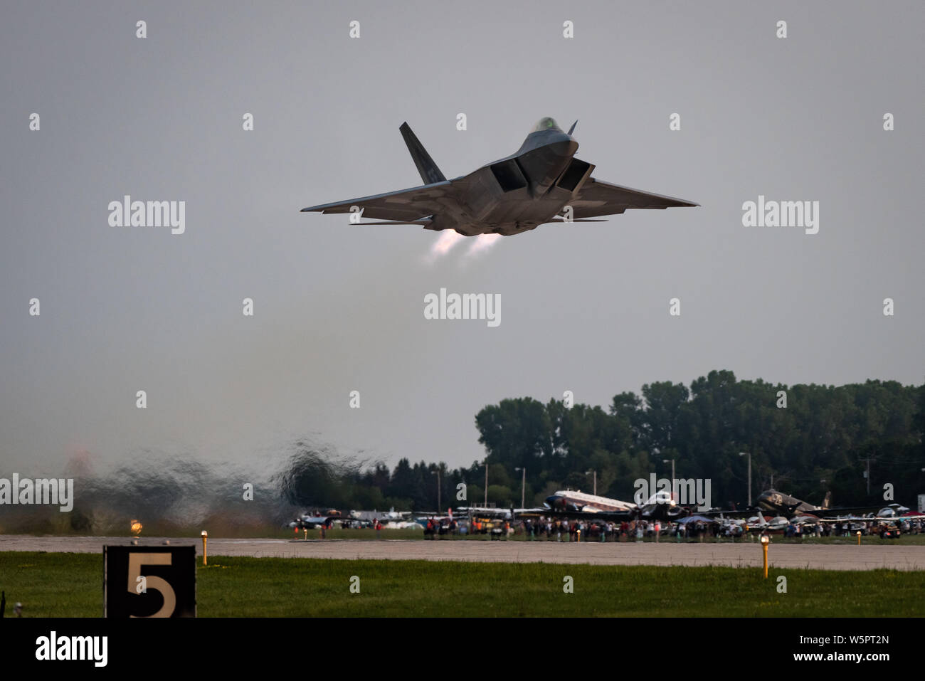 U.S. Air Force Maj. Paul Lopez, F-22 Demo Team commander, performs a twilight demonstration during EAA AirVenture in Oshkosh, Wis., July 28, 2019. Representing the U.S. Air Force and Air Combat Command, the F-22 Demo Team travels to over 20 air shows a season to showcase the performance and capabilities of the world's premier 5th-generation fighter. (U.S. Air Force photo by 2nd Lt. Samuel Eckholm) Stock Photo