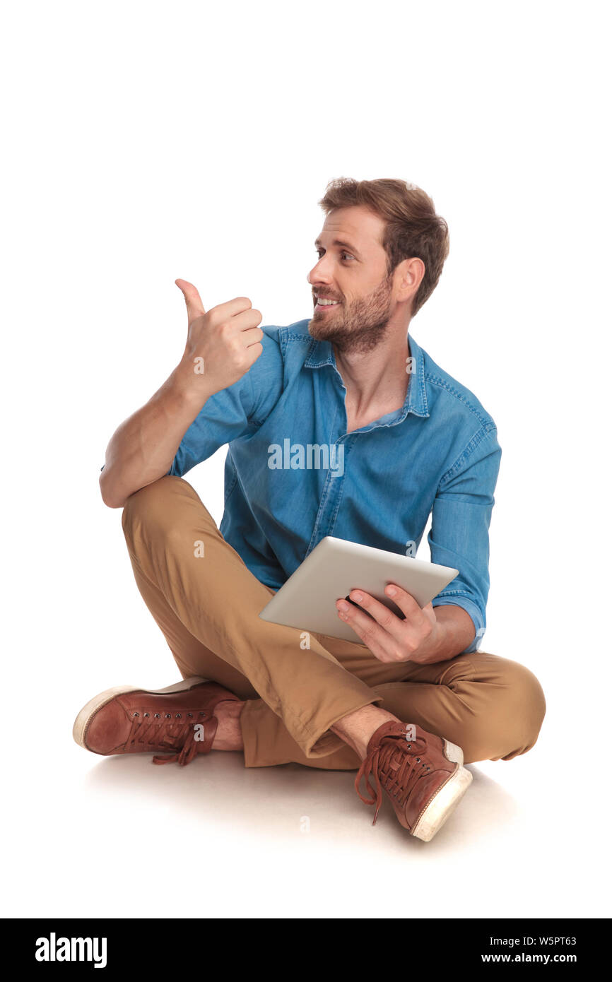 seated casual man with tablet pointing or making the ok sign on white ...