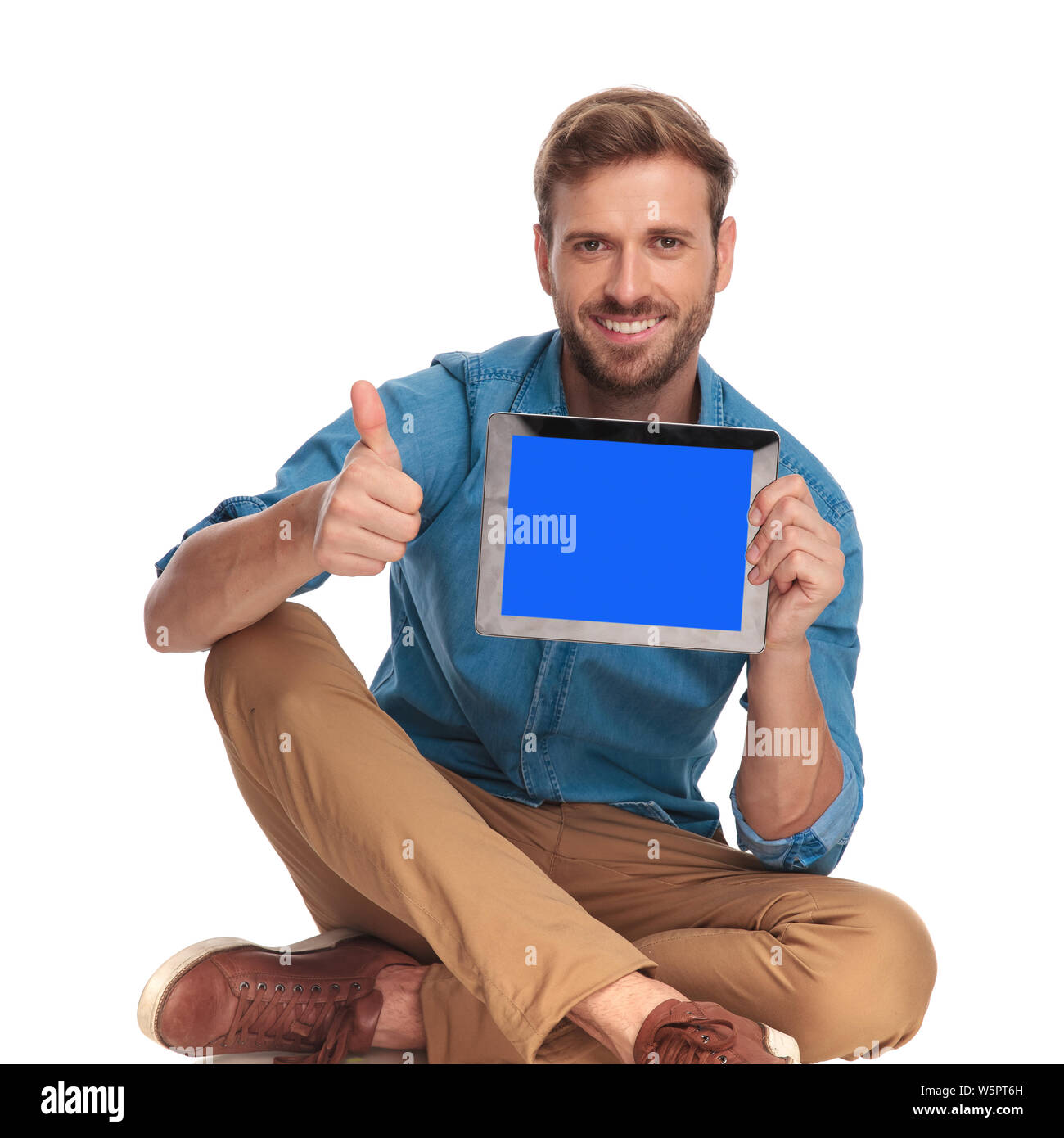 seated casual man showing the screen of tablet and makes ok sign on ...