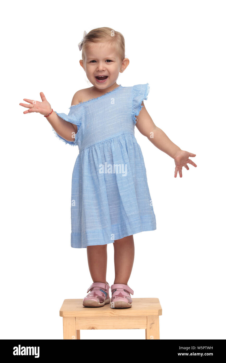 joyful little girl in blue dress welcomes you while standing on a ...