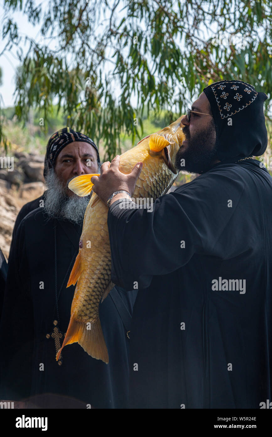Tabgha, Israel - May 18 2019 : Coptic monk at Tabgha church beside Sea of Galilee holding a big fish Stock Photo