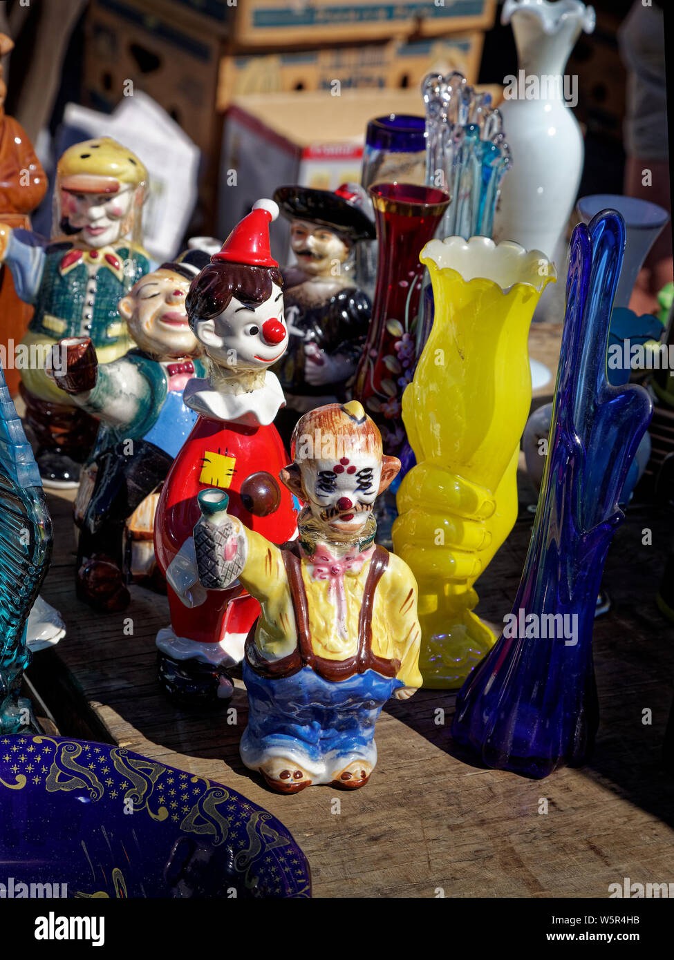 Colourful china figurines among glass vases on a Motueka market stall. New Zealand. Stock Photo