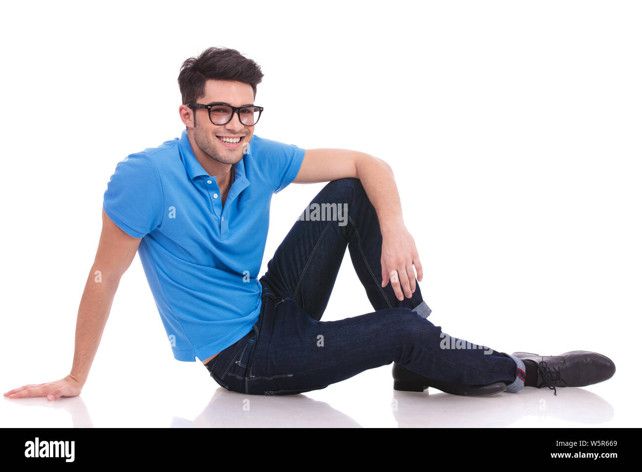 relaxed casual man sitting down on the floor on white background Stock ...